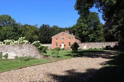 an old brick house with a stone wall and trees at Garden House at Woodhall Estate in Hertford
