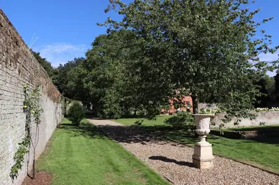 a vase sitting in the grass next to a wall at Garden House at Woodhall Estate in Hertford