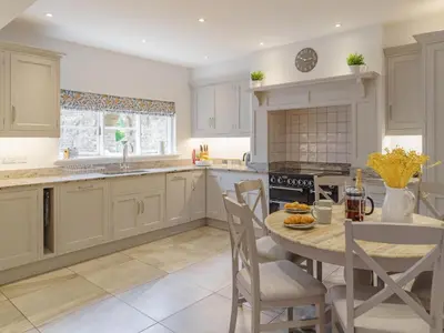 a kitchen with white cabinets and a table and chairs at Garden House at Woodhall Estate in Hertford