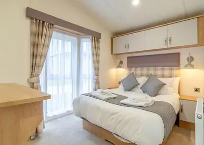 a bedroom with a large bed and a large window at Woolverstone Marina and Lodge Park in Ipswich