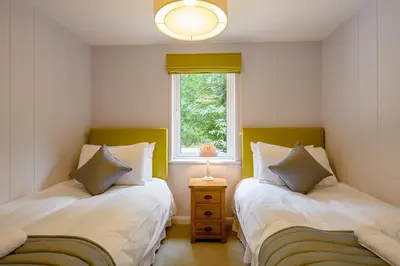 two twin beds in a room with a window at Woolverstone Marina and Lodge Park in Ipswich