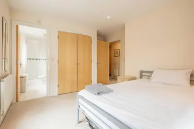a bedroom with a large white bed and a closet at 2 BR flat next to Train Station & Gated Parking in Cambridge