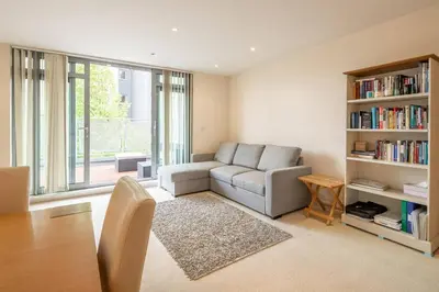 a living room with a couch and a book shelf at 2 BR flat next to Train Station & Gated Parking in Cambridge