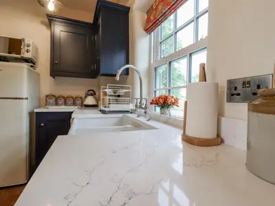 a kitchen with a white counter top and a sink at Postbox Cottage in Thetford