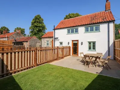 a backyard with a wooden fence and a table and chairs at Postbox Cottage in Thetford