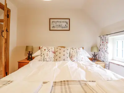 a bedroom with a white bed and a window at Postbox Cottage in Thetford