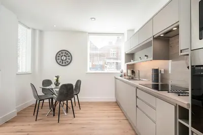 a kitchen with white cabinets and a table and chairs at Citystay Living - Dutch's Corner in Cambridge