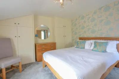 a bedroom with a bed and a chair and a mirror at Chapel Cottage, Newbourne in Newbourn