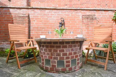 a brick fireplace with two chairs next to a brick wall at Chapel Cottage, Newbourne in Newbourn