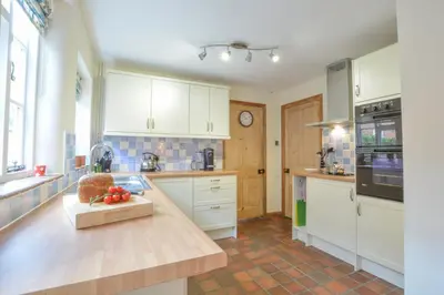 a kitchen with white cabinets and a wooden counter top at Chapel Cottage, Newbourne in Newbourn