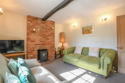 a living room with a green couch and a fireplace at Chapel Cottage, Newbourne in Newbourn