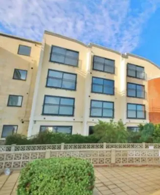 a white building with a fence in front of it at Penthouse Apartment with seaviews in Walton-on-the-Naze