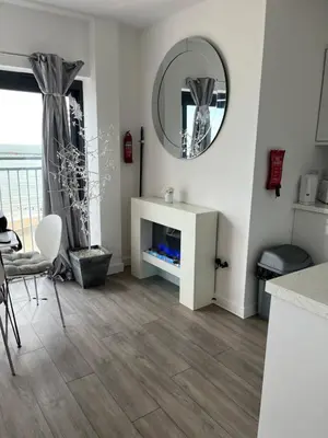 a living room with white walls and a mirror at Penthouse Apartment with seaviews in Walton-on-the-Naze