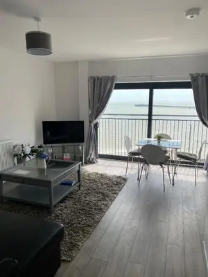 a living room with a table and a view of the ocean at Penthouse Apartment with seaviews in Walton-on-the-Naze