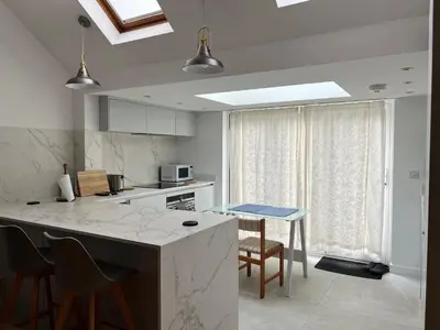 a kitchen with a counter and a kitchen island with chairs at 300m to Fitzwilliam museum 3 en-suites double bedroom Victoria house in Cambridge