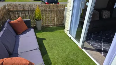 a couch sitting on the grass outside of a house at None available in Jaywick Sands
