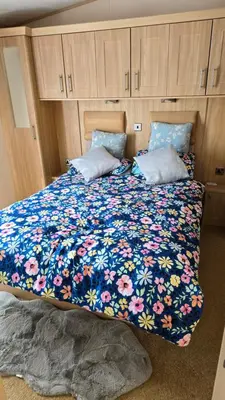 a bed with a blue blanket with flowers on it at None available in Jaywick Sands