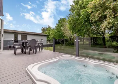 a hot tub on a deck with a table and chairs at The Essex Golf And Country Club in Markshall