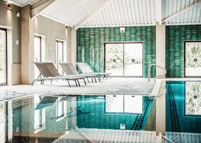 a swimming pool with chairs in a large room at The Essex Golf And Country Club in Markshall