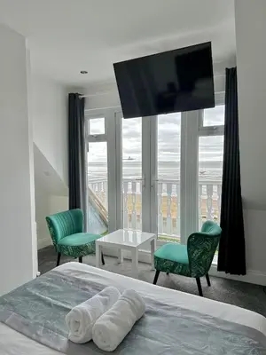 a bedroom with a bed with two chairs and a television at WNS Southend-on-Sea in Southend-on-Sea