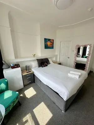 a bedroom with a large bed and a chair at WNS Southend-on-Sea in Southend-on-Sea