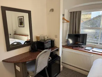a hotel room with a desk with a television and a mirror at Kings Lodge in Newmarket