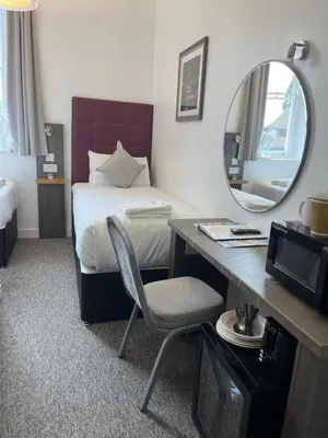 a bedroom with a bed with a mirror and a desk at Kings Lodge in Newmarket