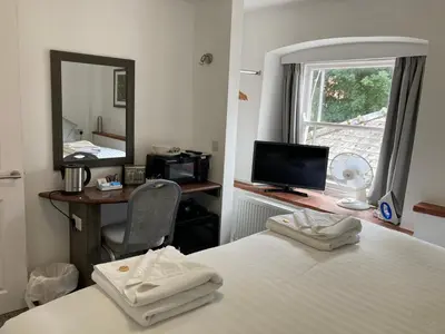 a bedroom with two beds and a desk and a mirror at Kings Lodge in Newmarket