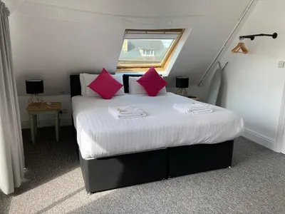 a bedroom with a bed with pink pillows and a window at Kings Lodge in Newmarket