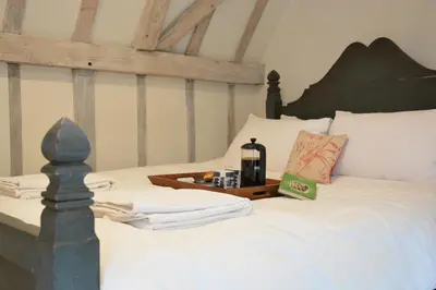 a bedroom with a white bed with a wooden headboard at The Gig House, Stowupland in Stowmarket