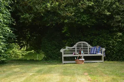 a white bench sitting in the grass with a basket at The Gig House, Stowupland in Stowmarket