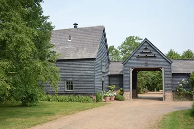 a black barn with an archway in a yard at The Gig House, Stowupland in Stowmarket