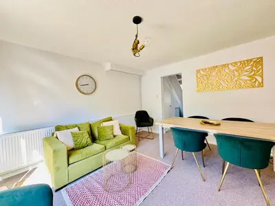 a living room with a green couch and a table at The Jade House - Cambridge Rental with Garden and BBQ, Near City Centre in Cambridge