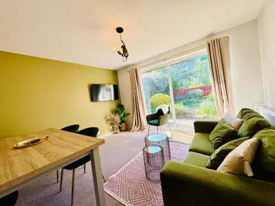 a living room with a green couch and a table at The Jade House - Cambridge Rental with Garden and BBQ, Near City Centre in Cambridge