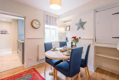 a dining room with a table and chairs and a clock at Periwinkle Cottage, Aldeburgh in Aldeburgh