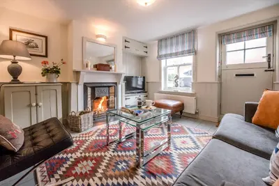 a living room with a table and a fireplace at Periwinkle Cottage, Aldeburgh in Aldeburgh
