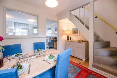 a dining room with a wooden table and blue chairs at Periwinkle Cottage, Aldeburgh in Aldeburgh