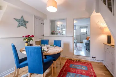 a dining room with a table and blue chairs at Periwinkle Cottage, Aldeburgh in Aldeburgh