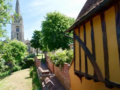 a building next to a church with a tower at Executive Suite with Private HotTub, Full SkyTV in 600 Year Old Manor House in Saffron Walden
