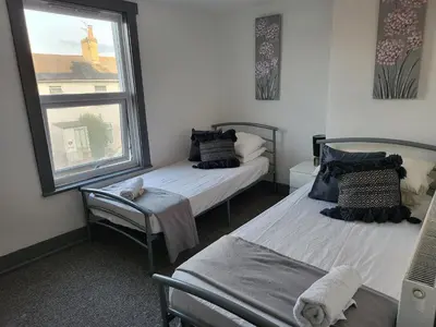 a bedroom with two beds and a window at Colchester House with garden and parking- Sleeps up to 7 - Free Wi-Fi - Contractors - Families - Long Term Stays in Colchester