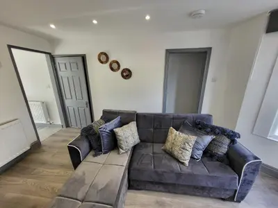 a living room with a brown leather couch with pillows at Colchester House with garden and parking- Sleeps up to 7 - Free Wi-Fi - Contractors - Families - Long Term Stays in Colchester