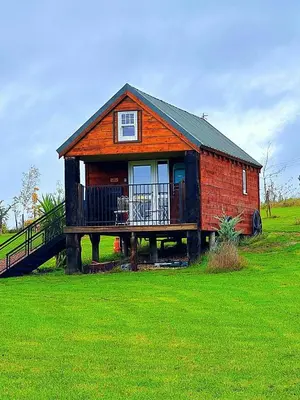 a small house with a deck on a green field at Lake View Lodges The Kentwell in Long Melford