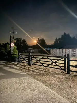 a fence in front of a building with the sunset in the background at Lake View Lodges The Kentwell in Long Melford