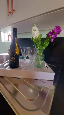 a bottle of wine and two glasses and flowers on a counter at Lake View Lodges The Kentwell in Long Melford