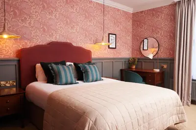 a bedroom with a large bed and pink wallpaper at Dog and Partridge by Greene King Inns in Bury Saint Edmunds