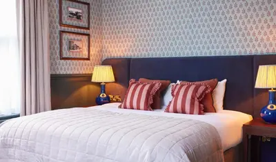 a bedroom with a large bed with red and white pillows at Dog and Partridge by Greene King Inns in Bury Saint Edmunds