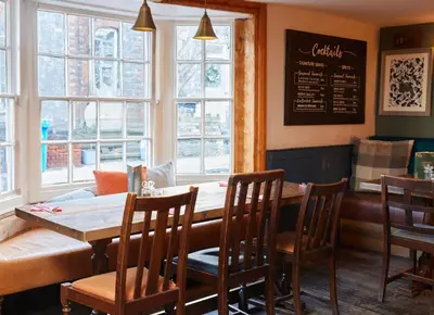 a dining room with a table and chairs and windows at Dog and Partridge by Greene King Inns in Bury Saint Edmunds