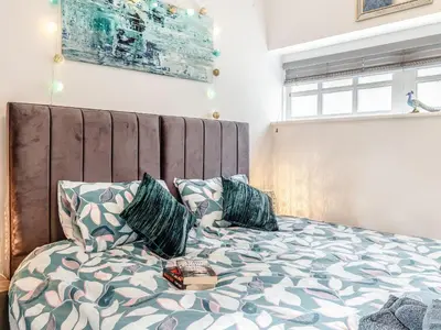 a bedroom with a bed with a large headboard and pillows at Peacock On The Pin in Stisted
