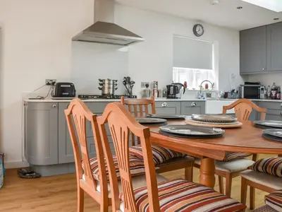 a kitchen with a wooden table and wooden chairs at Sunnyside in Colchester