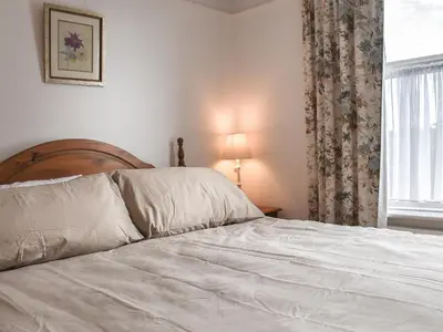a bed with white sheets in a bedroom with a window at Sunnyside in Colchester